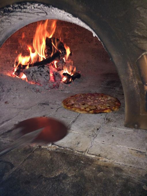 pizza che viene girata nel forno a legna antico