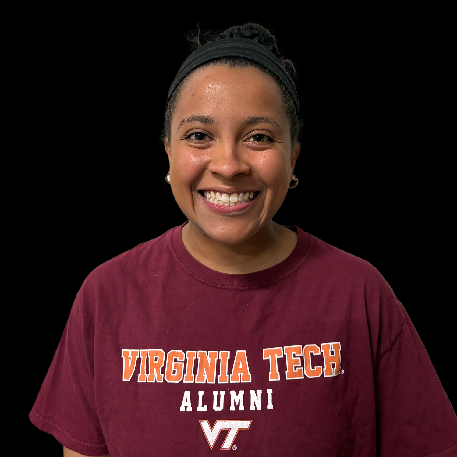 Smiling person in a maroon Virginia Tech alumni T-shirt against a black background