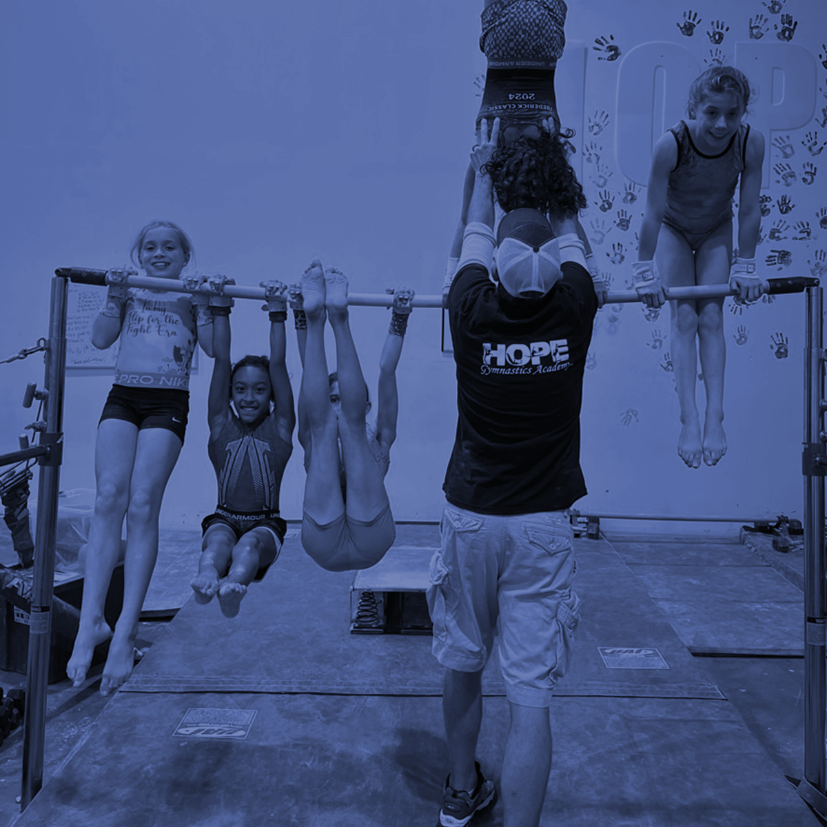 A young girl is sitting on a balance beam in a gym.