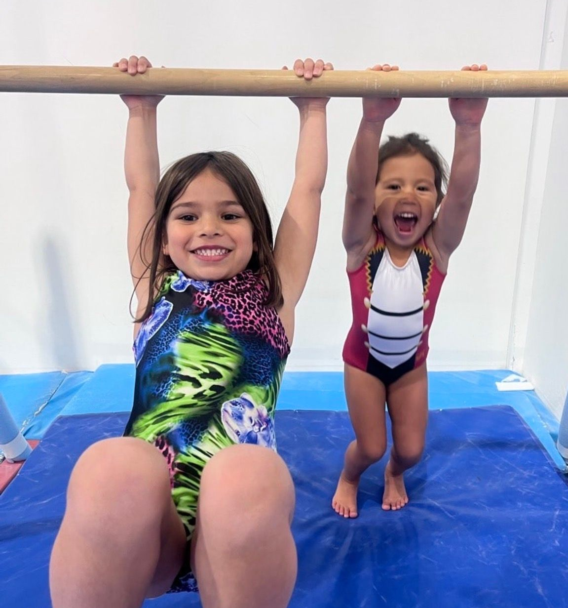 A gymnast in a purple leotard is standing on a balance beam