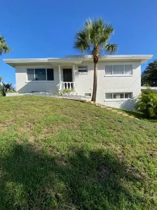 A white house with a palm tree in front of it.