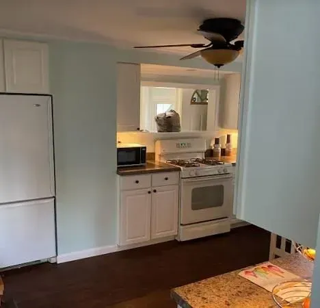 A kitchen with a stove , refrigerator , microwave and ceiling fan.