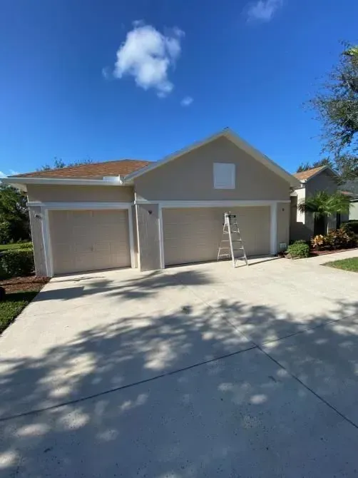 A house with two garage doors and a ladder in front of it.