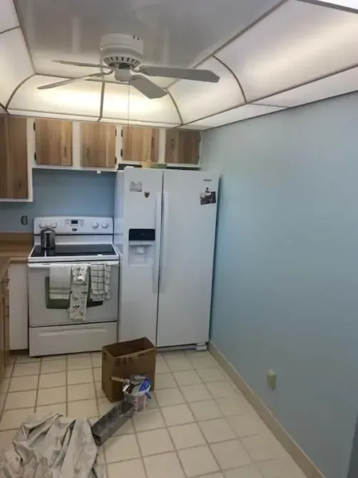 A kitchen with a stove a refrigerator and a ceiling fan