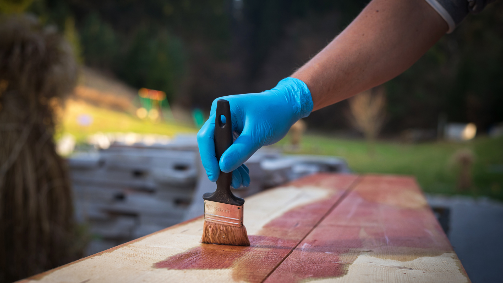A person is painting a wooden table with a brush.