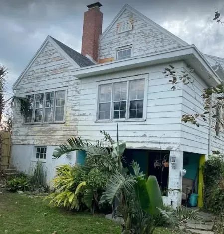 A white house with a red chimney and a lot of windows