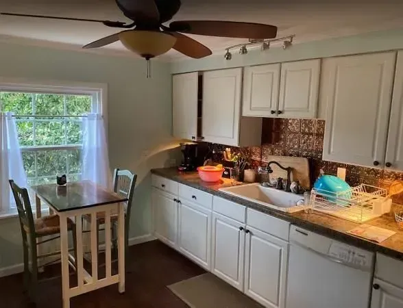A kitchen with white cabinets and a ceiling fan