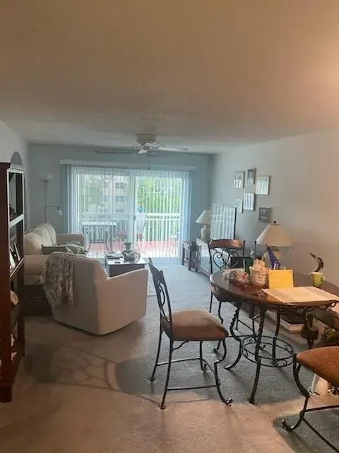 A living room with a table and chairs and a sliding glass door.
