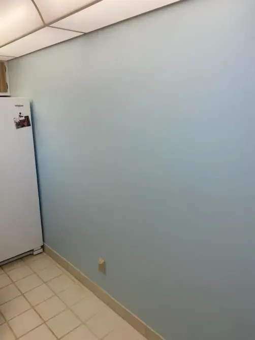 A kitchen with blue walls and a white refrigerator.