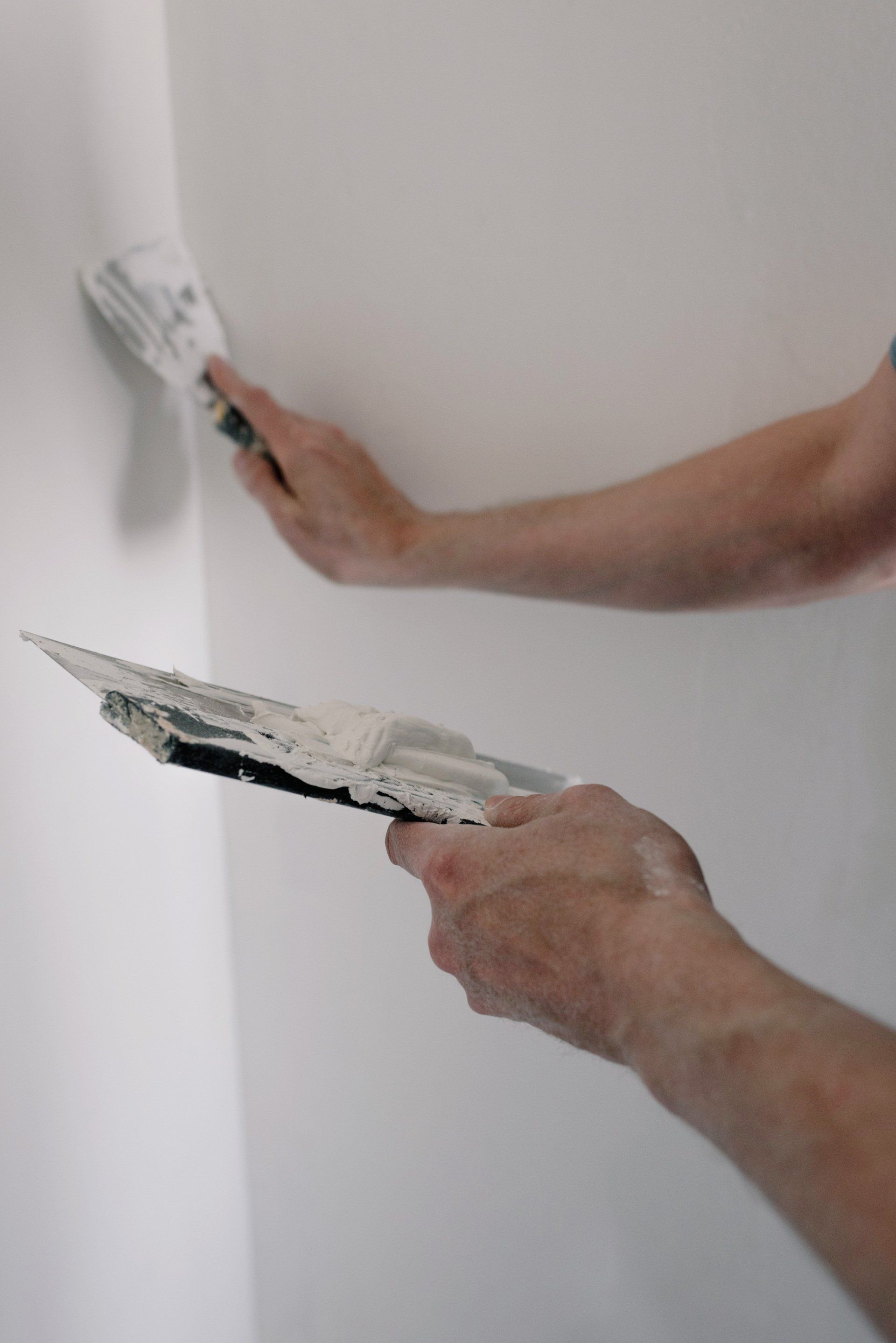A person is plastering a wall with a spatula and brush.