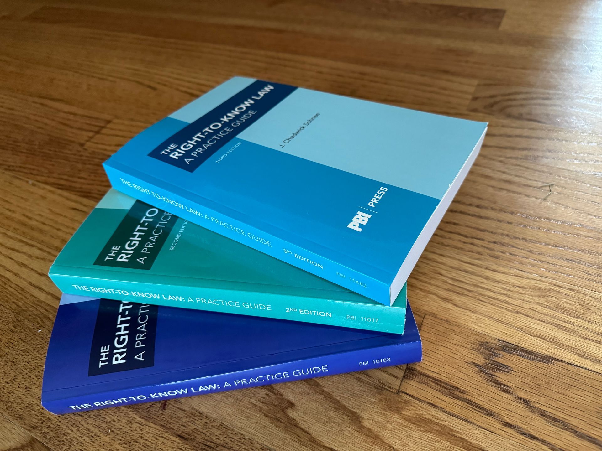 Three books are stacked on top of each other on a wooden floor