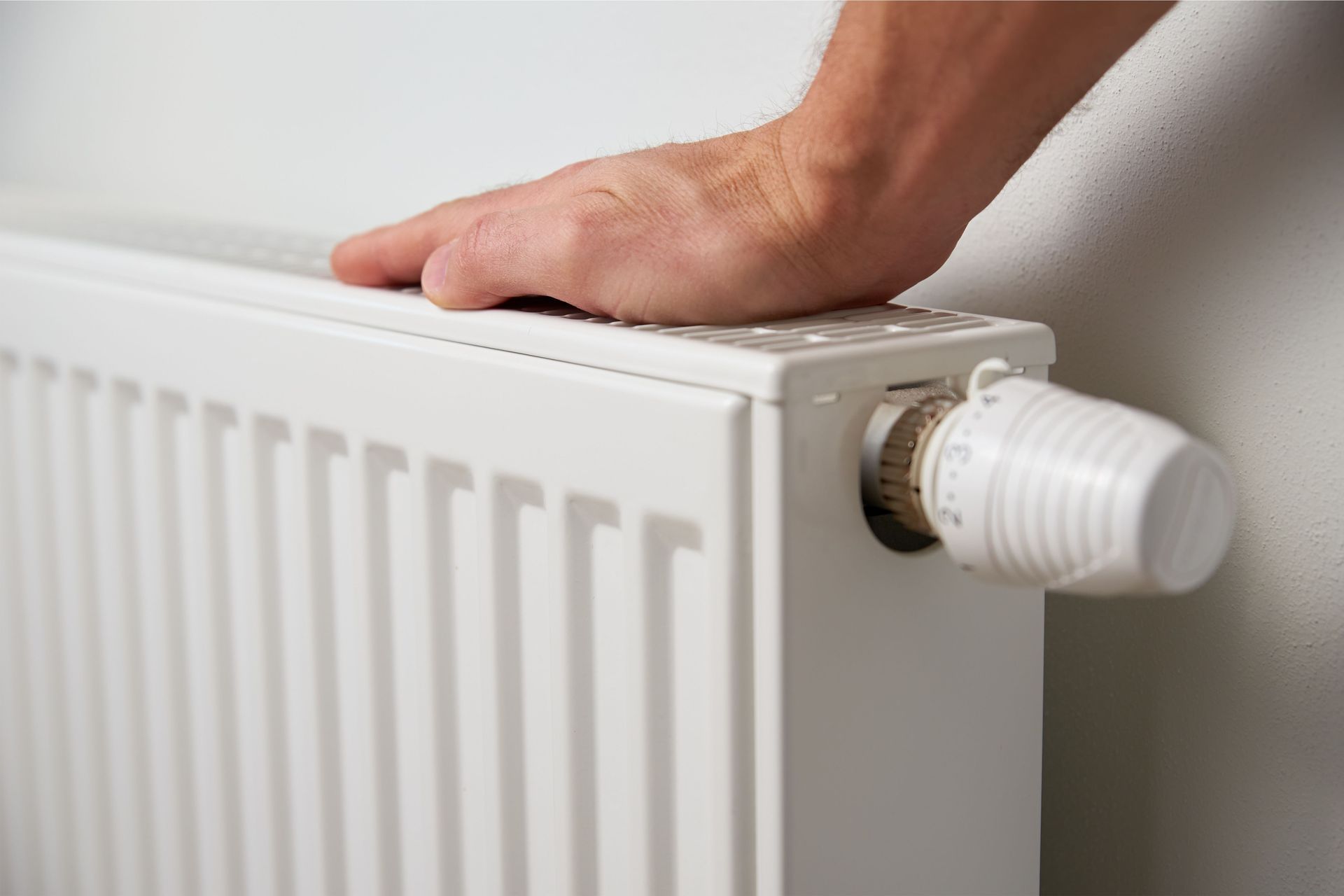 A person is adjusting a radiator with their hand.