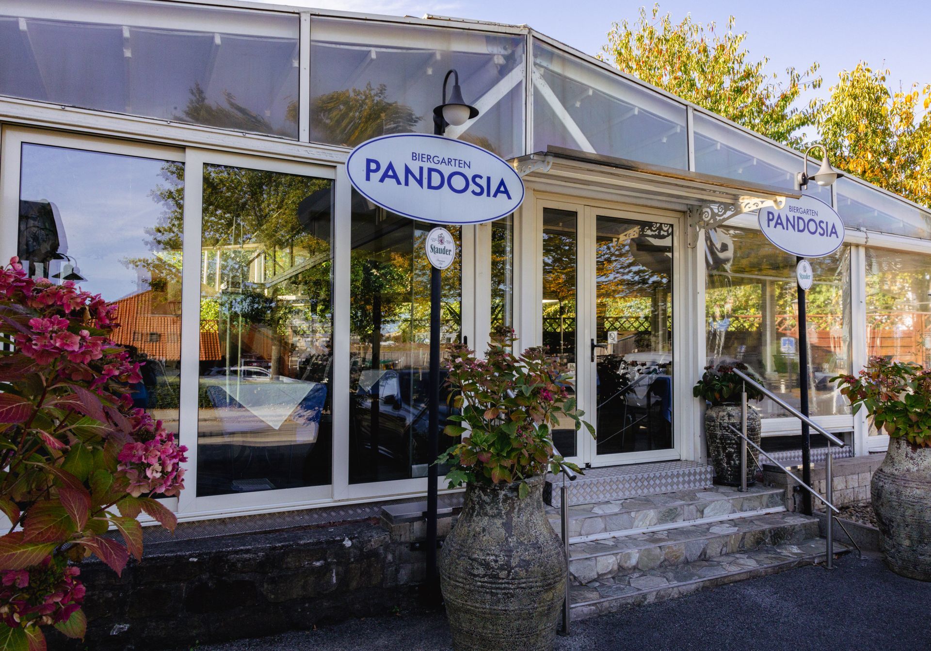 Restauranteingang mit großen Fenstern und einem Schild mit der Aufschrift „Pandosia“.