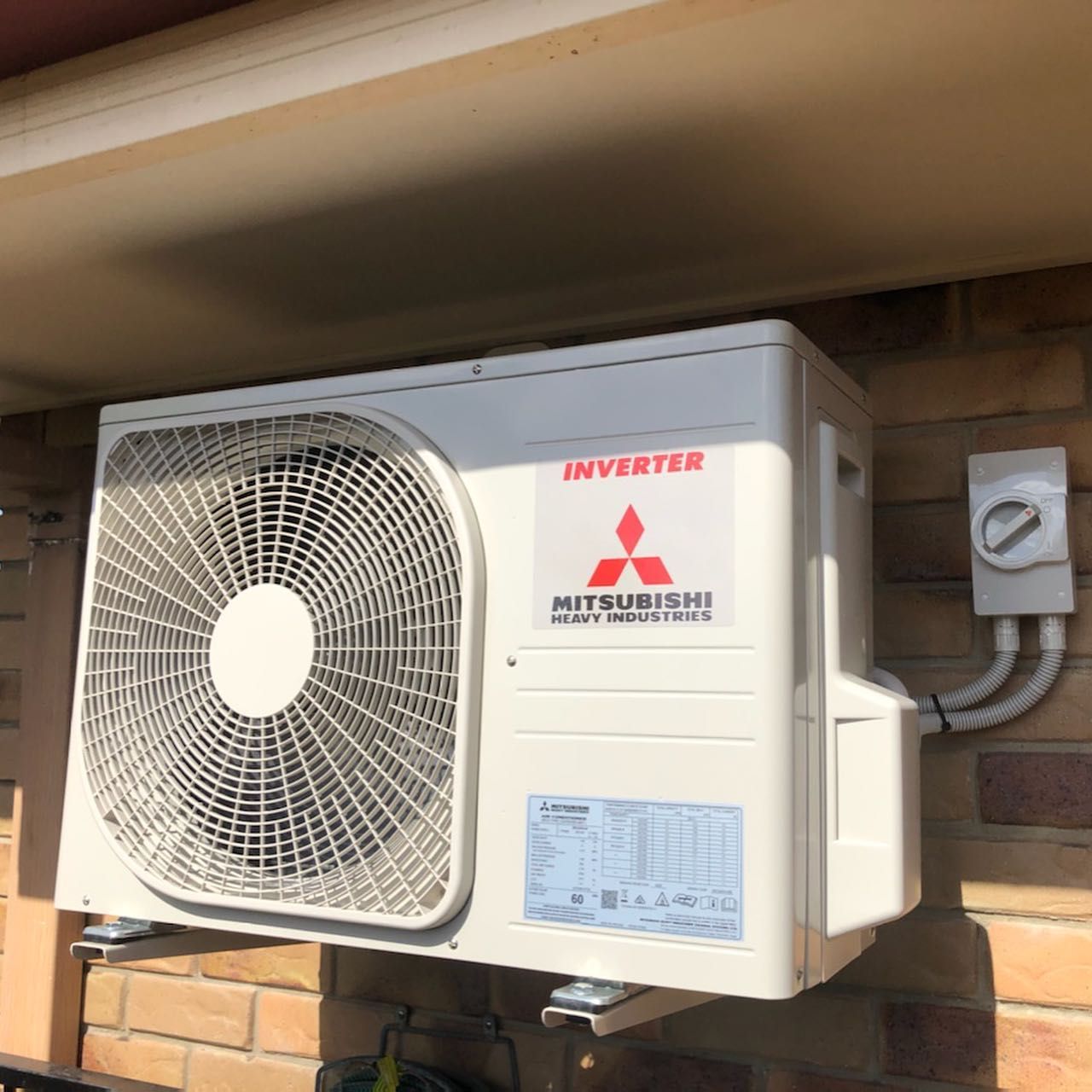 A Mitsubishi Air Conditioner Is Mounted on A Brick Wall — Paton's Electrical Services in Torquay, QLD