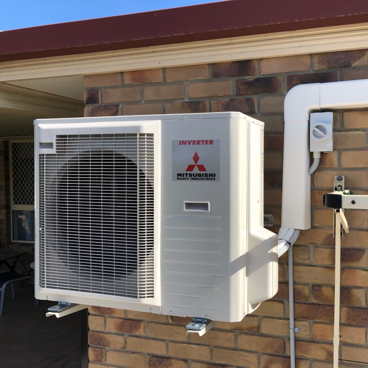 A White Air Conditioner Is Hanging on A Wall — Paton's Electrical Services in Pialba, QLD