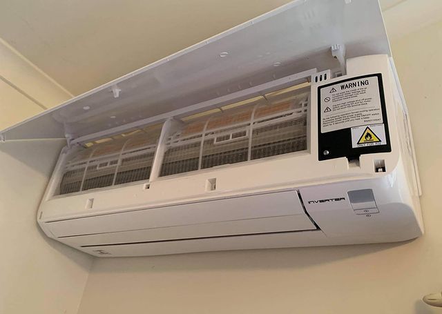 A White Air Conditioner Is Hanging from The Ceiling in A Room — Paton's Electrical Services in Pialba, QLD