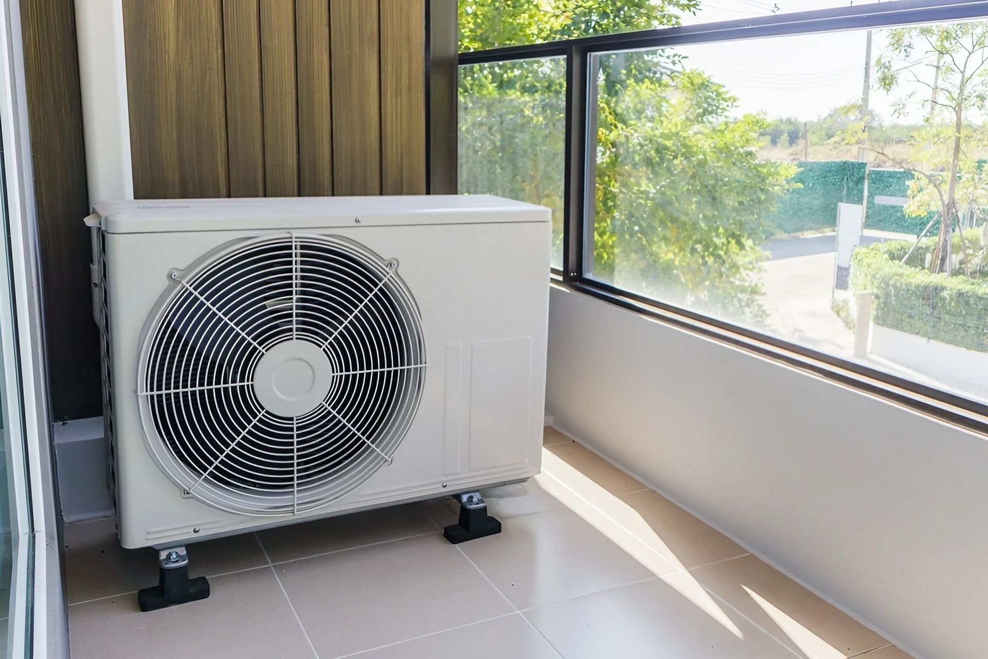 A White Air Conditioner Is Hanging on A Wall — Paton's Electrical Services in Hervey Bay, QLD