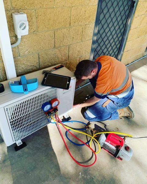 A Man Is Working on An Air Conditioner Outside of A Building — Paton's Electrical Services in Pialba, QLD