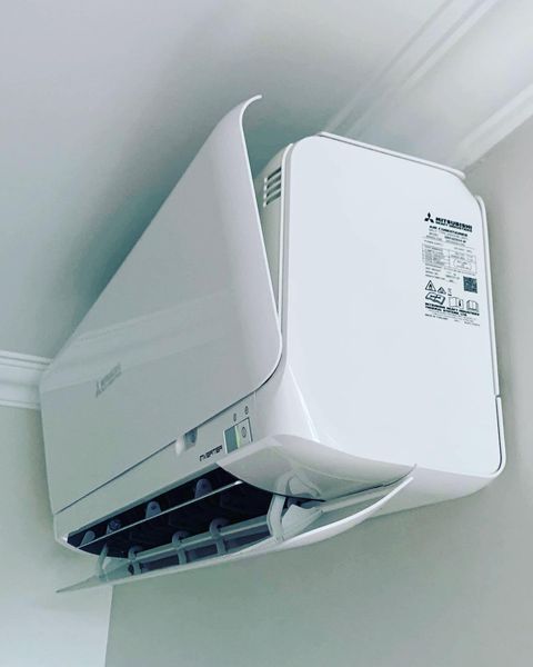 A White Air Conditioner Is Hanging from The Ceiling in A Room — Paton's Electrical Services in Maryborough, QLD