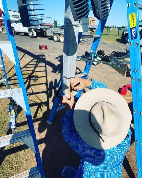 A Man Wearing a Hat Is Working on A Ladder — Paton's Electrical Services in K'Gari, QLD