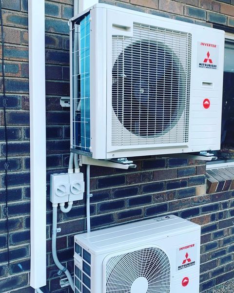 A Mitsubishi Air Conditioner Is Mounted on A Brick Wall — Paton's Electrical Services in K'Gari, QLD