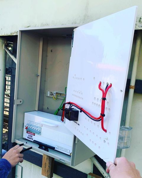 A Person Is Working On An Electrical Box With The Door Open — Paton's Electrical Services in K'Gari, QLD