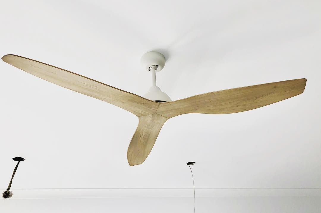A White Ceiling Fan with Wooden Blades Is Hanging from The Ceiling — Paton's Electrical Services in K'Gari, QLD