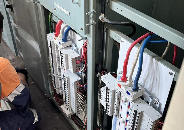 A Man Is Kneeling Down In Front Of A Electrical Panel — Paton's Electrical Services in Maryborough, QLD