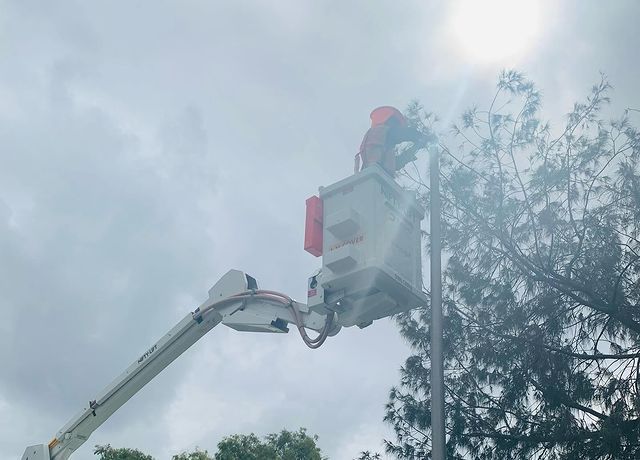 A Man in A Bucket Is Working on A Street Light — Paton's Electrical Services in Maryborough, QLD