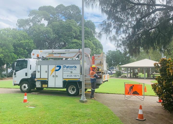 A Man Is Standing Next to A Truck in A Park — Paton's Electrical Services in Craignish, QLD