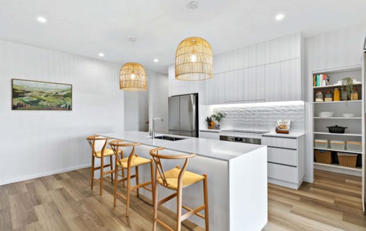 A Kitchen With White Cabinets And A Large Island — Paton's Electrical Services in Urangan, QLD