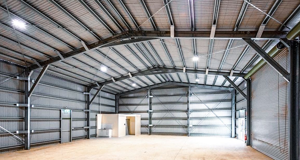 Two Men Are Working on A Ladder in A Garage — Paton's Electrical Services in Urangan, QLD