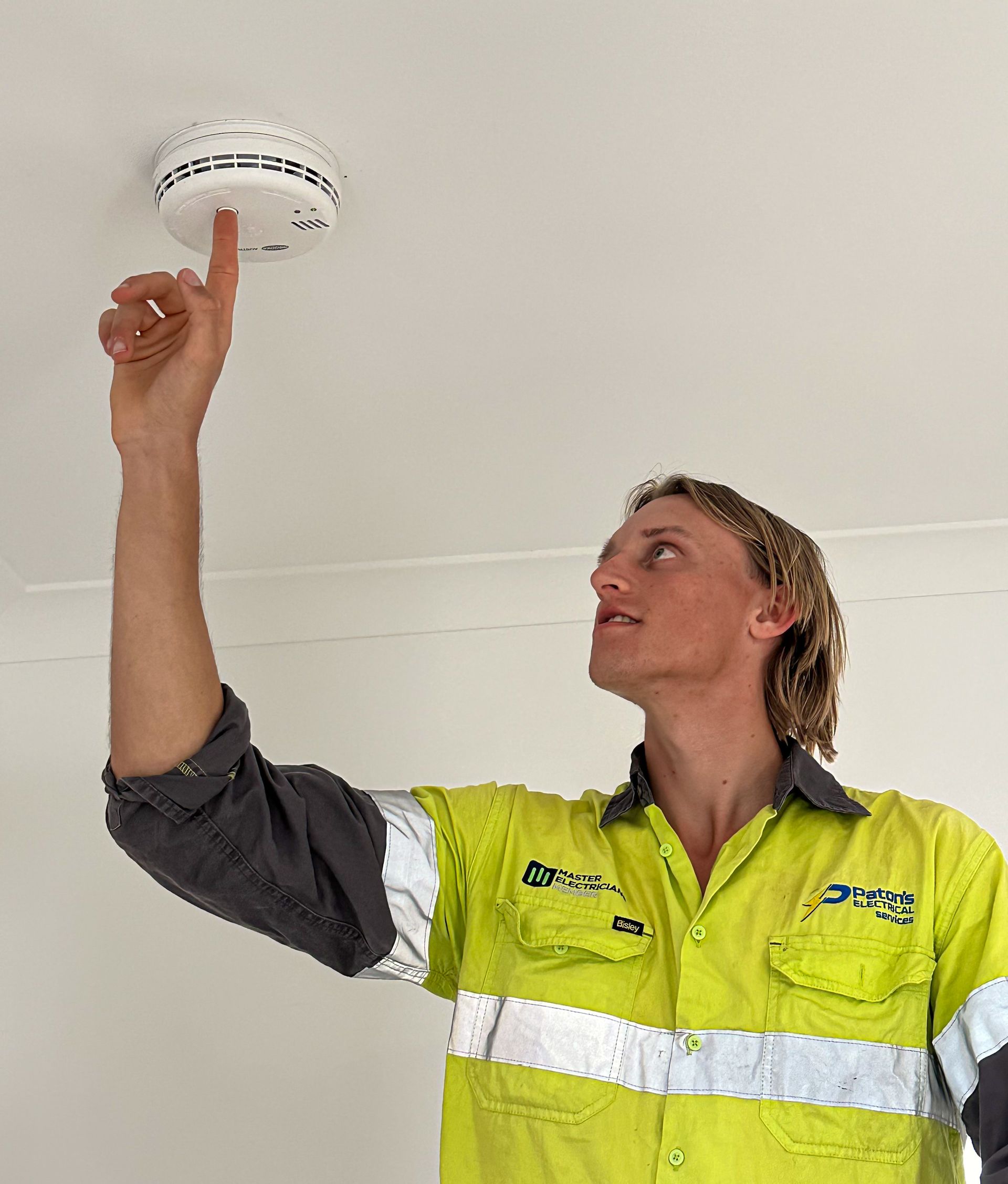 A Man Is Standing on A Ladder Working on A Ceiling — Paton's Electrical Services in Urangan, QLD