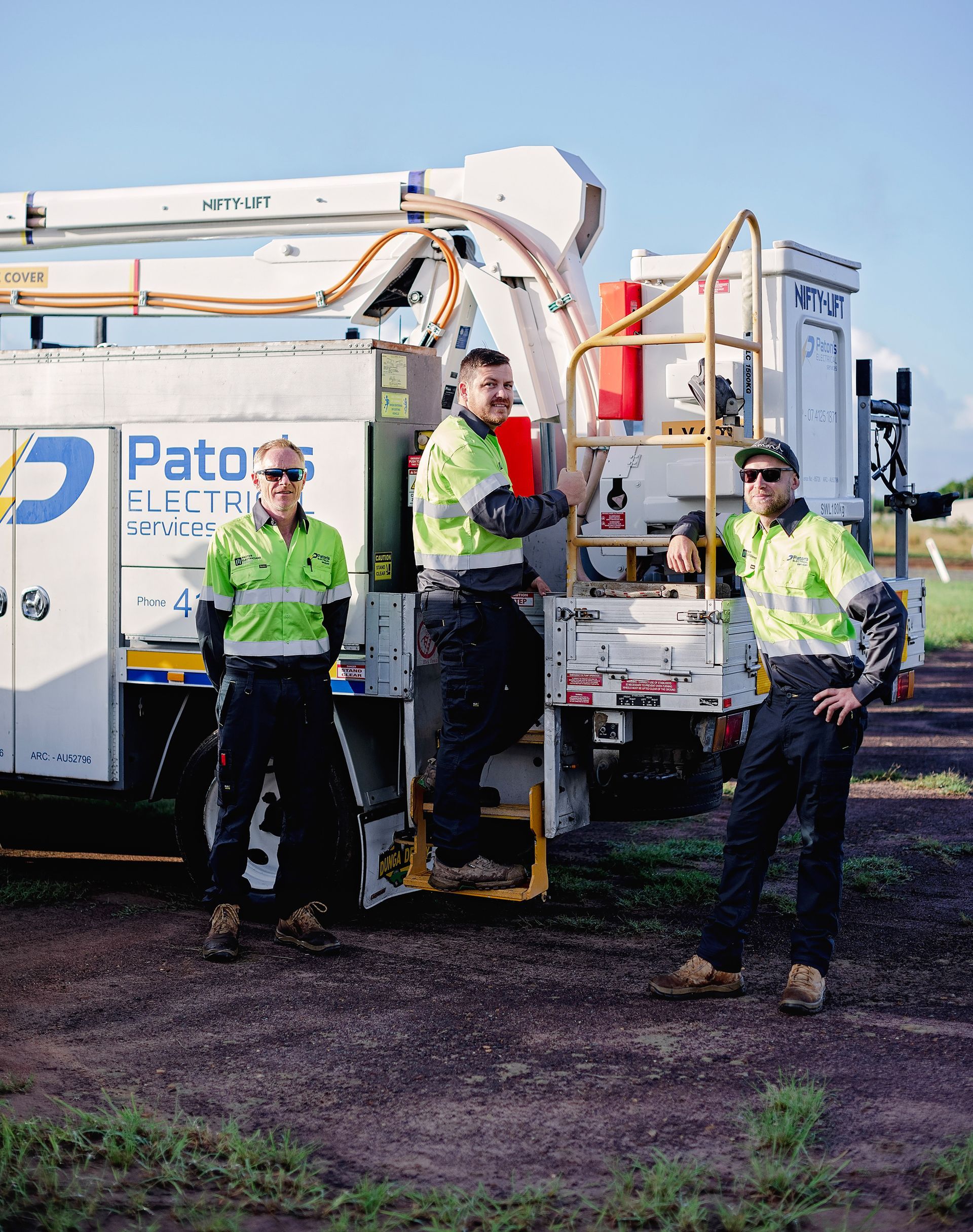 A Group Of Workers Are Standing In Front Of A Truck — Paton's Electrical Services in Urangan, QLD