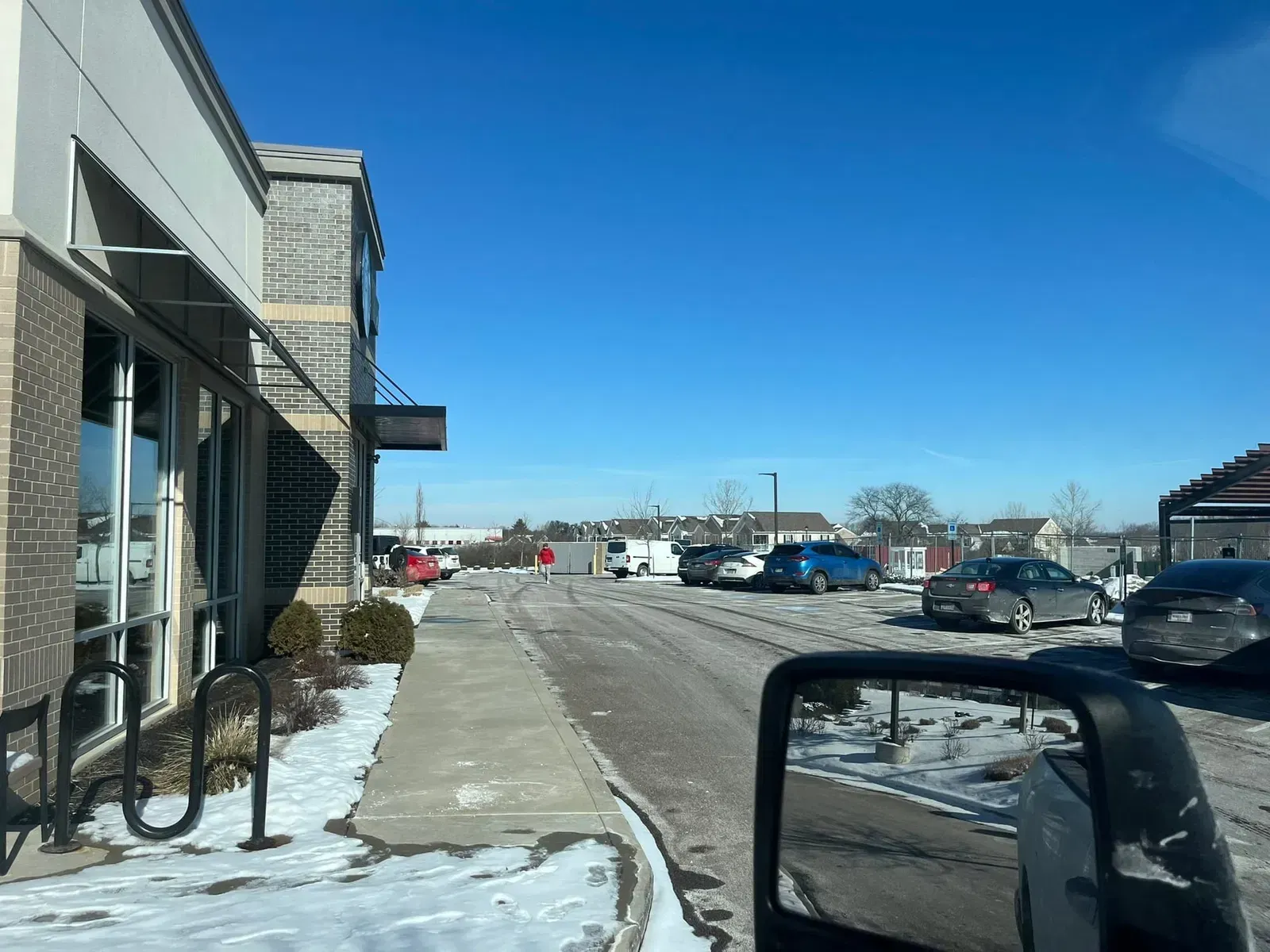 Exterior view of a building with a drive-thru lane on a snowy day, cars lined up.