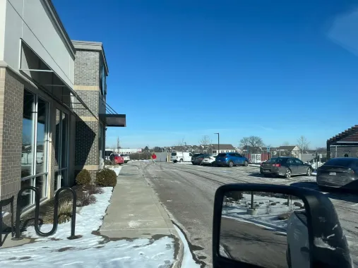 Exterior view of a building with a drive-through lane and several cars, snow on the ground.