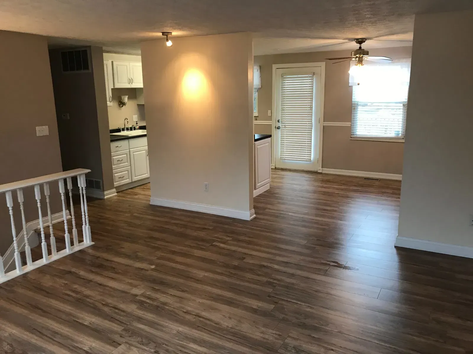 Interior view of a house with wood floors, open kitchen, and a doorway to a balcony.