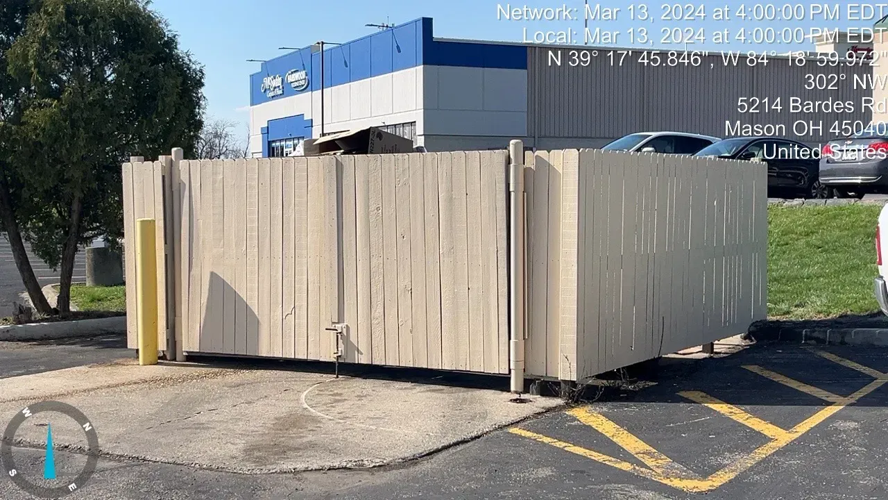 A beige wooden fence in front of a blue and white building, in Mason, OH.