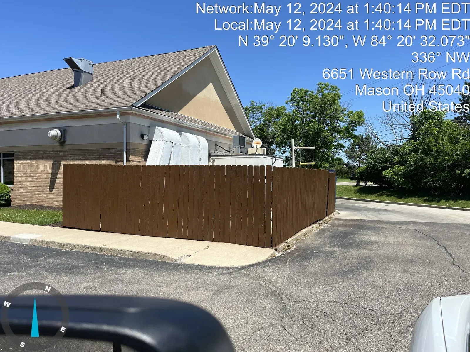 Brown wooden fence in front of a building, location details on top.