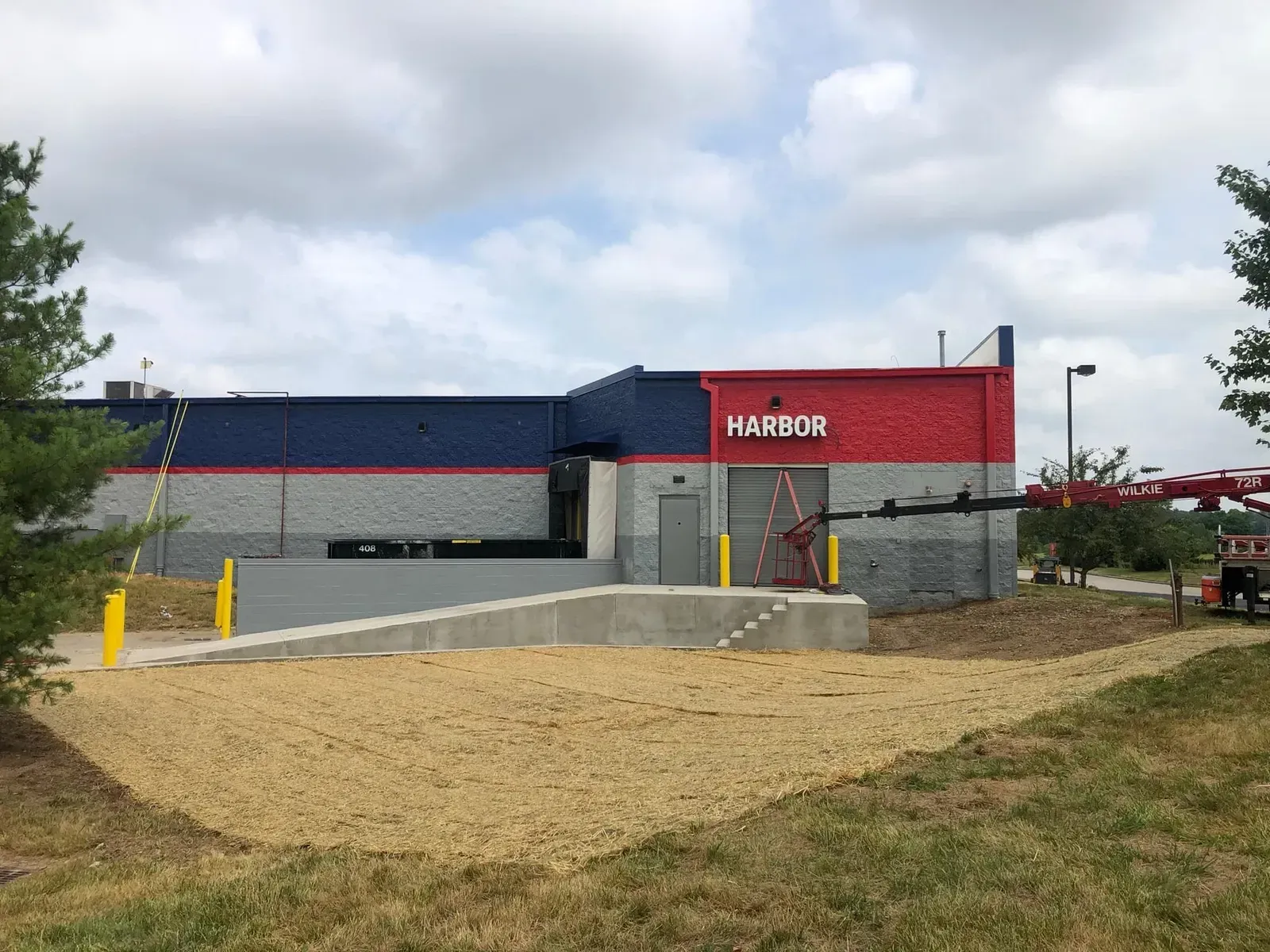 A building with a gray, red, and blue facade, with a concrete ramp leading up to an entrance.
