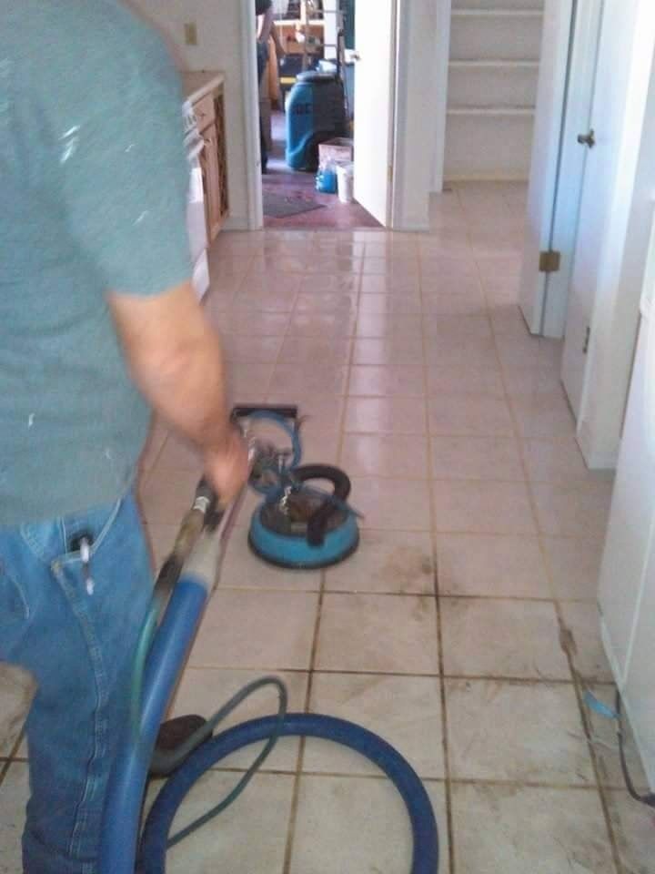 White pickup truck towing a black dump trailer on a grassy field under a blue sky.