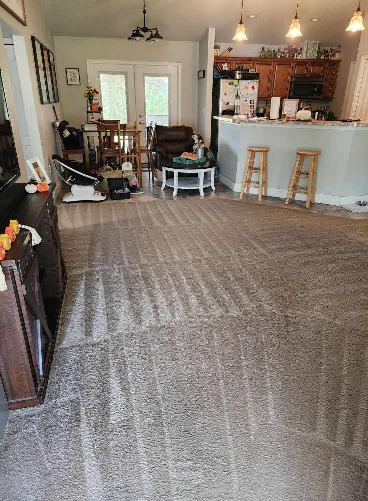 Black trailer with green signage parked next to green storage units. White pickup truck visible. Blue sky, clouds.