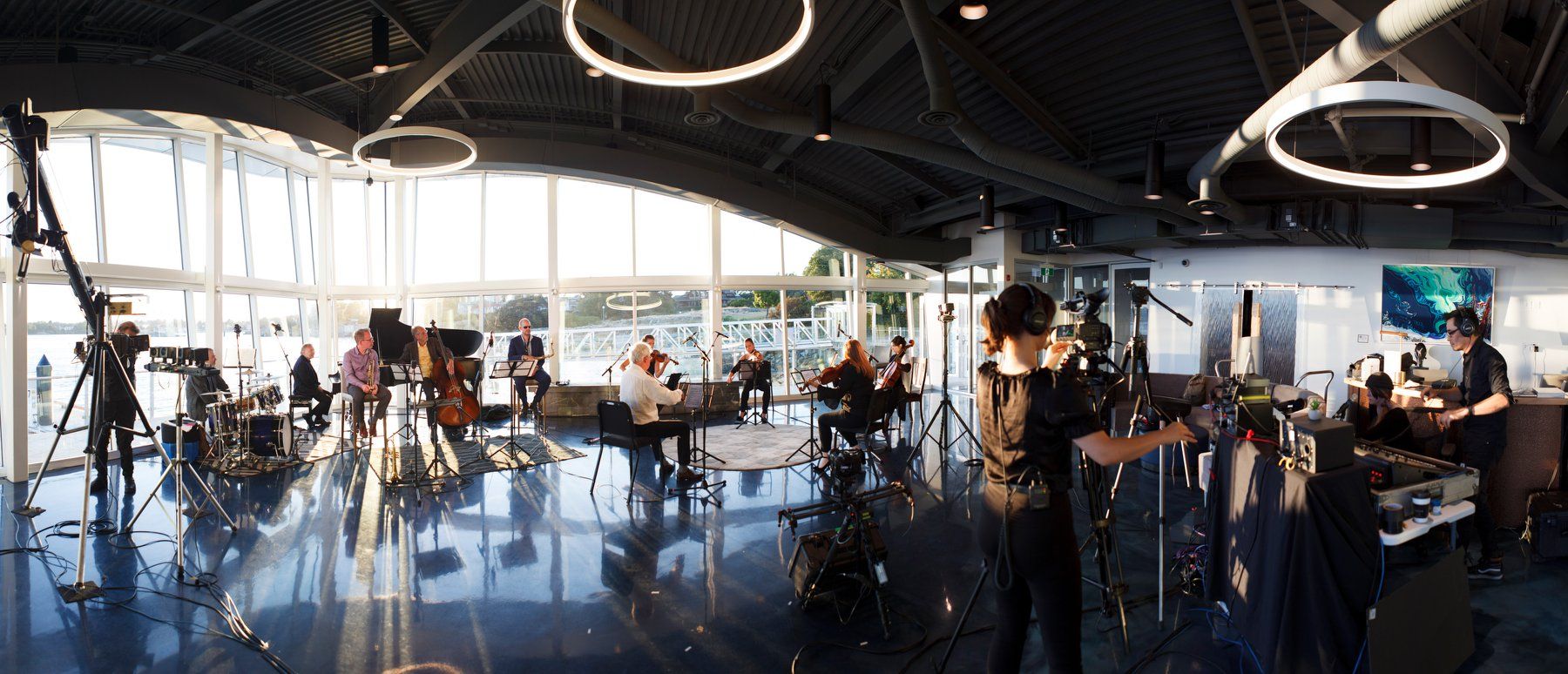 A group of people are standing in a large room with a lot of windows.