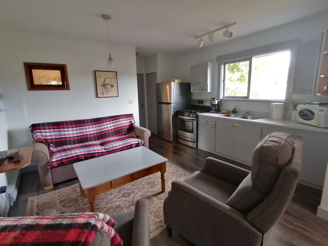A living room with a couch and chairs and a kitchen