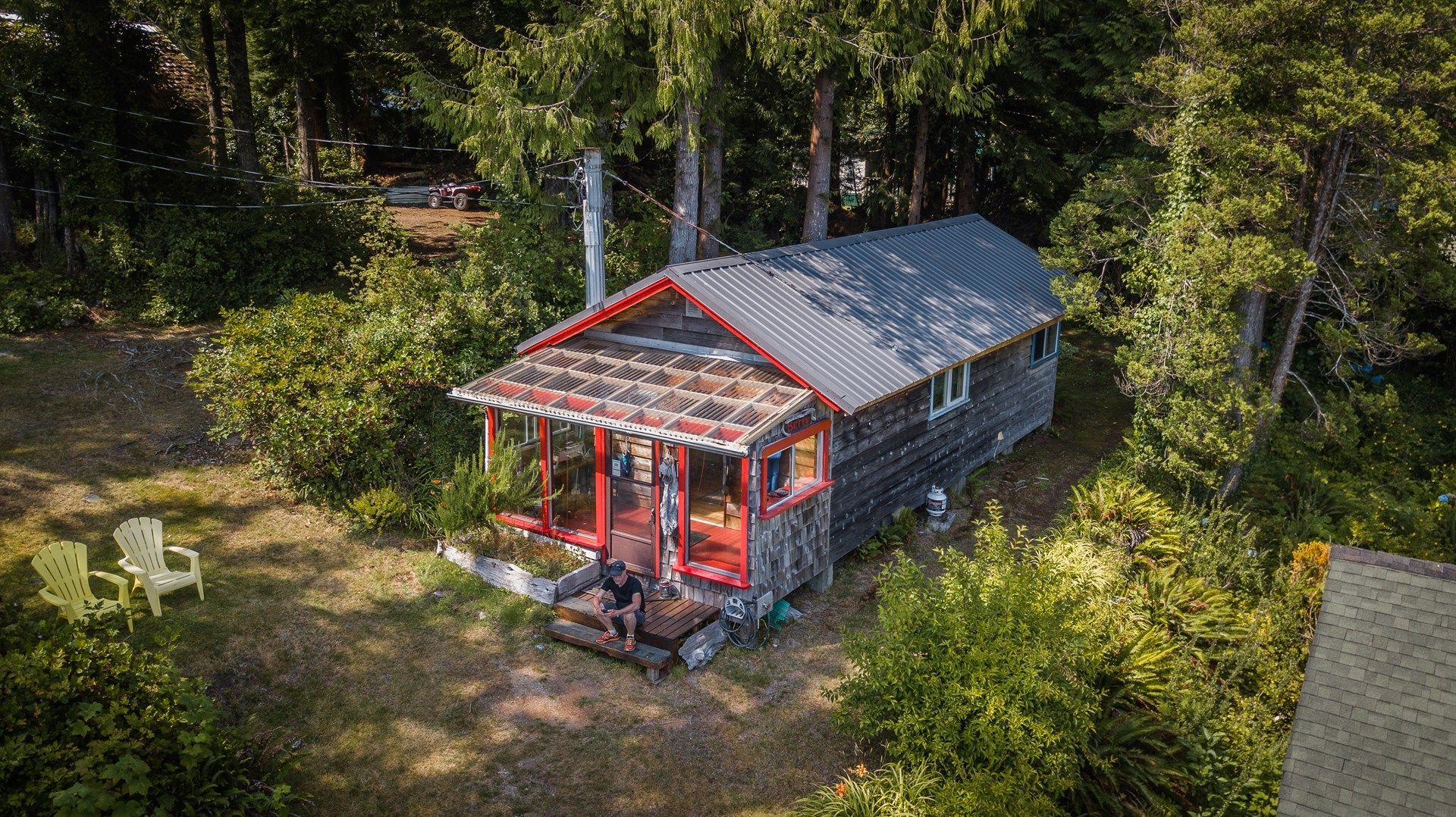 An aerial view of a small house in the middle of a forest.