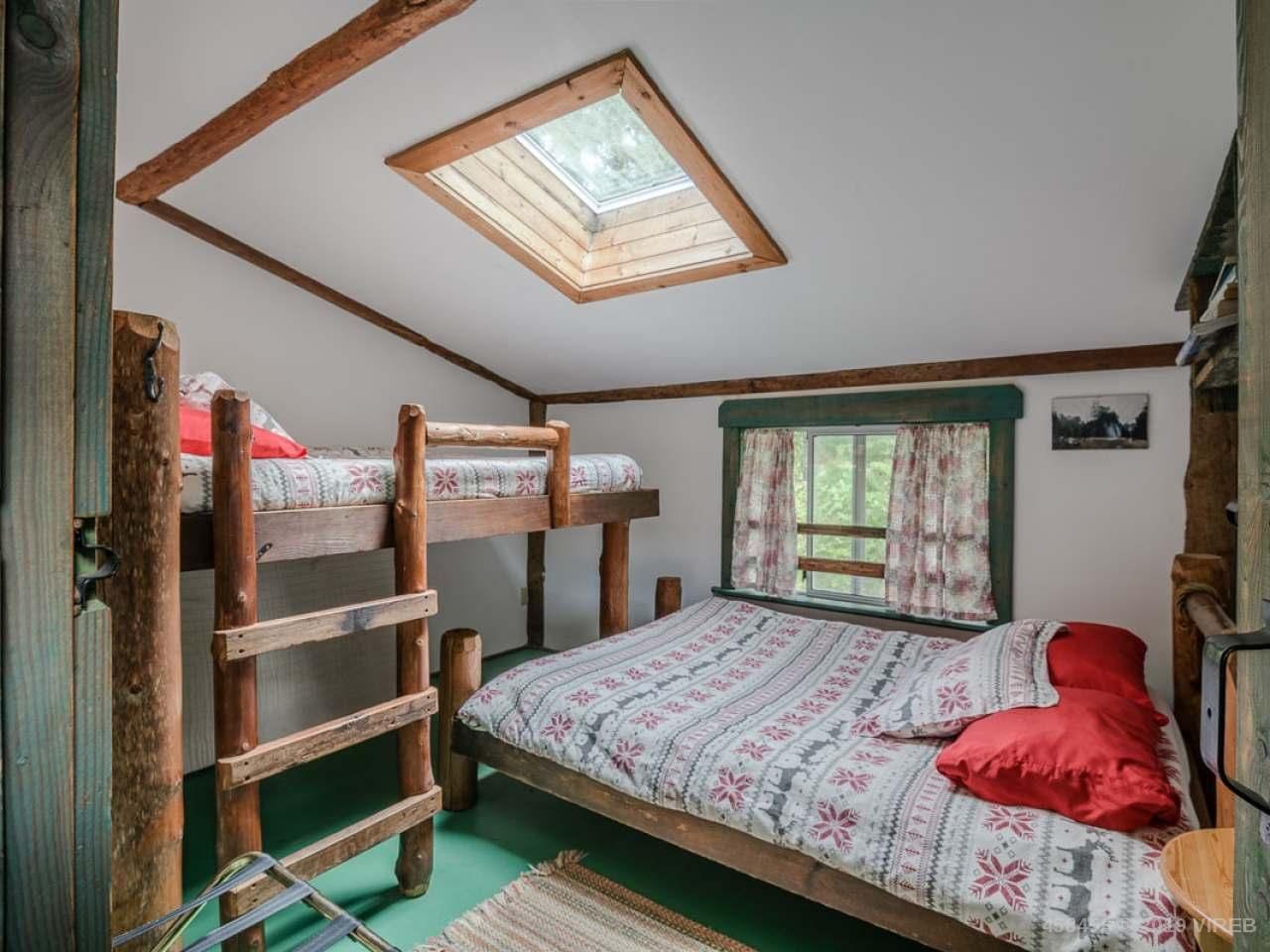 A bedroom with two bunk beds and a skylight.