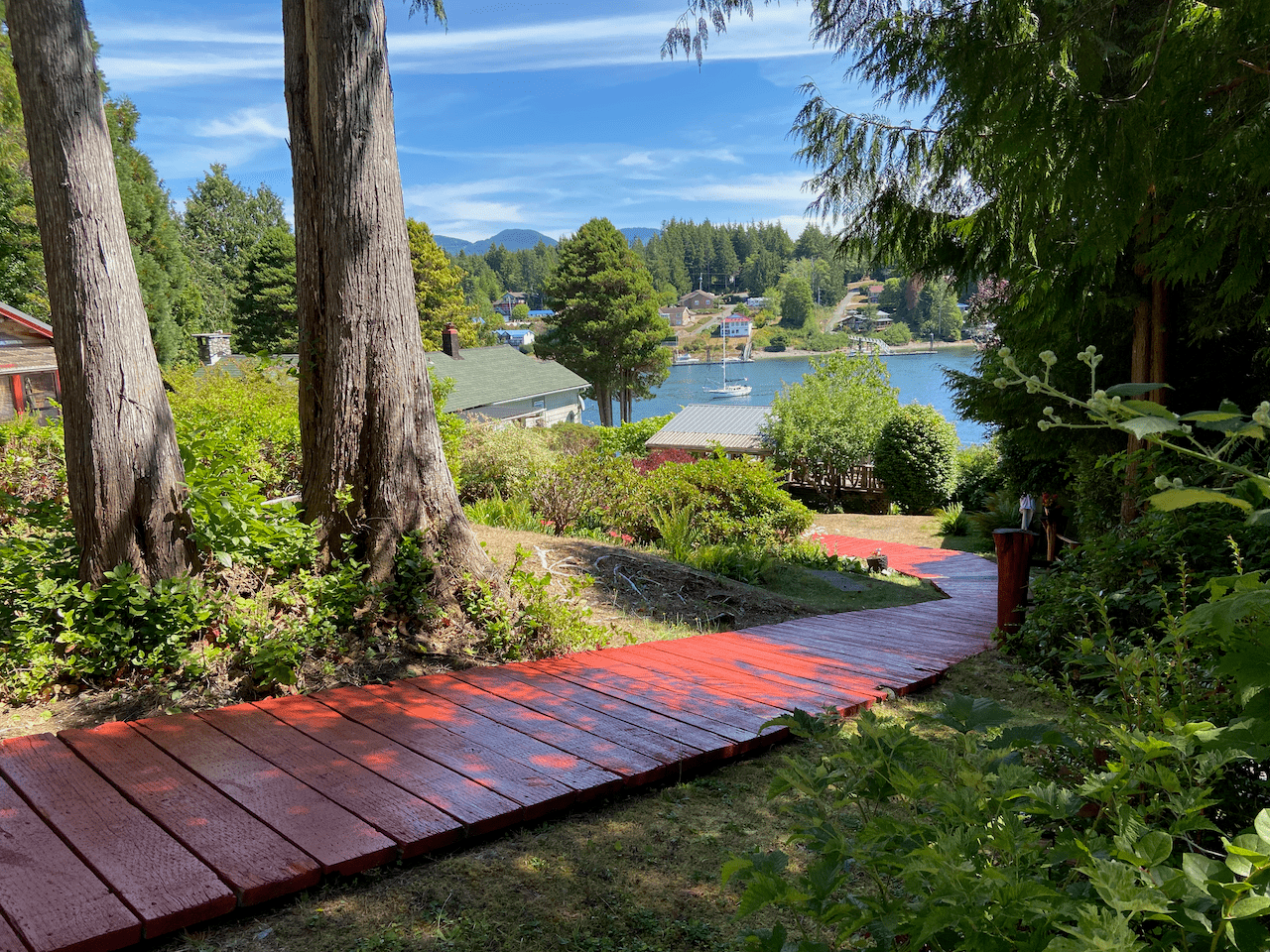 A wooden walkway leading to a lake surrounded by trees and bushes.