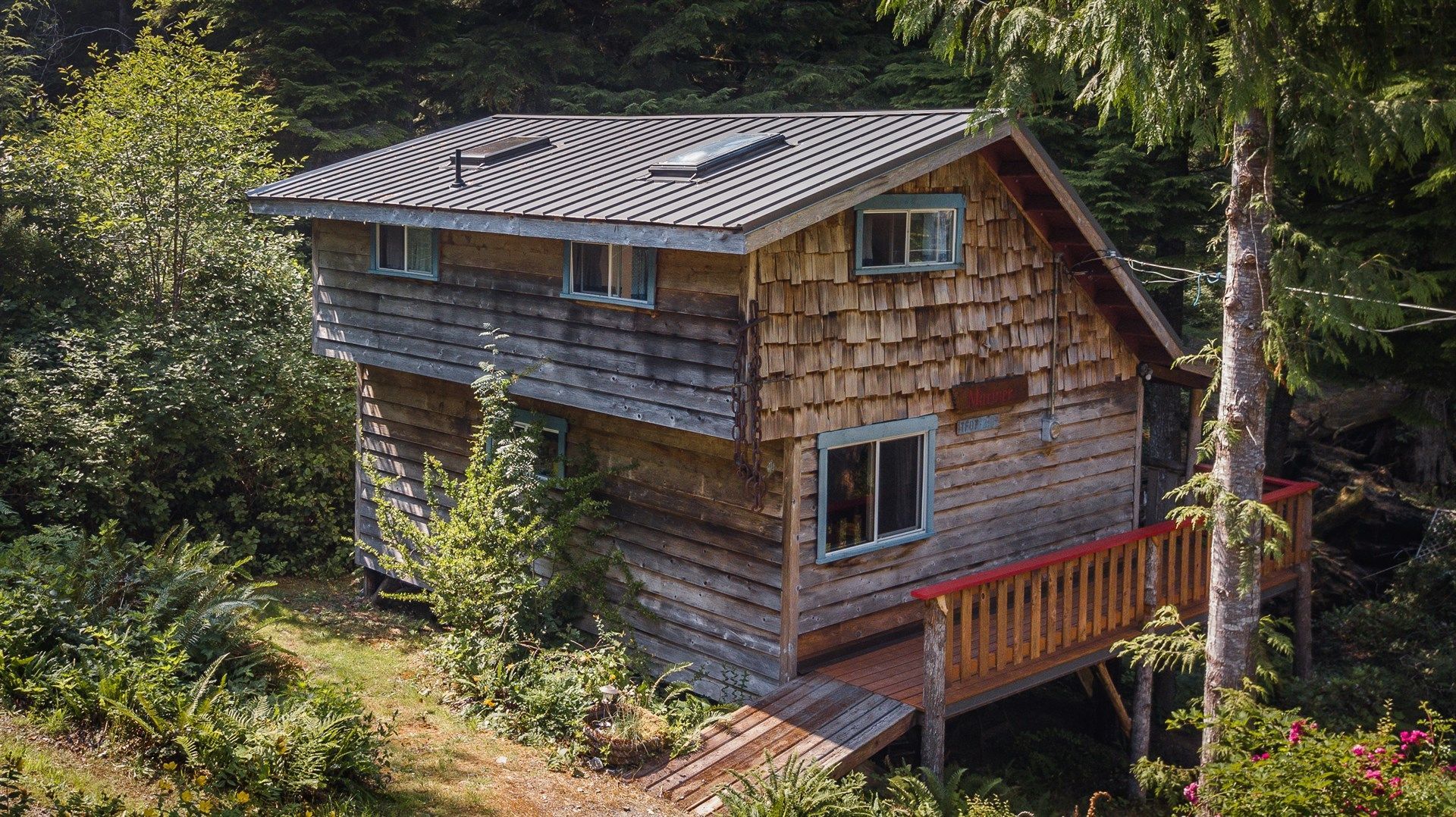 An aerial view of a small wooden house in the middle of a forest.