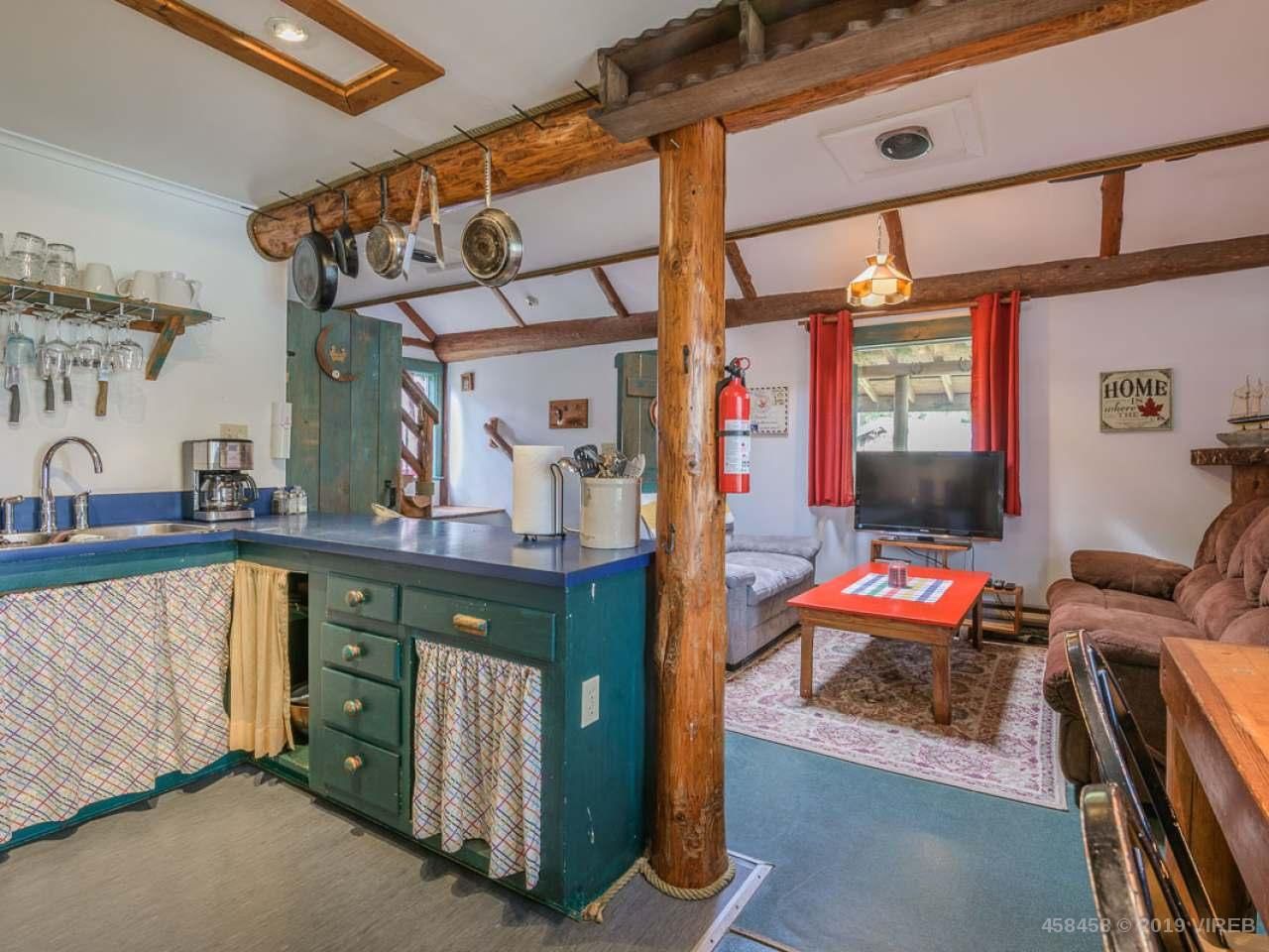 A kitchen and living room in a house with a fire extinguisher hanging from the ceiling.