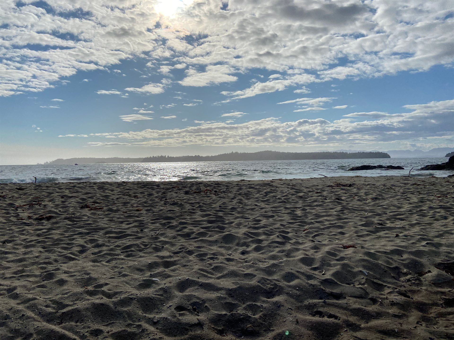 A sandy beach with a view of the ocean on a cloudy day.